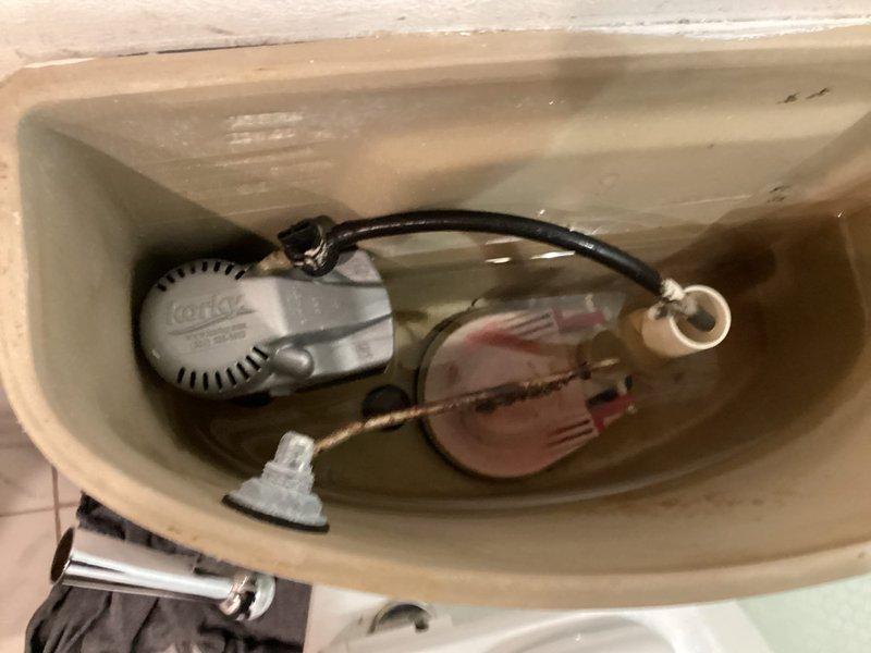 Responded to building shutdown service call. Inspected toilet mechanisms including Korky fill valve assembly and flush valve components. Documented condition of tank interior showing mineral deposits and water staining. Tank components appear functional.