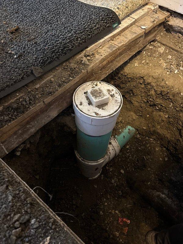 Excavated flooring and exposed subfloor joists to access and install new sewer line connection. Installed PVC pipe assembly with proper connections to existing drainage system. Client has paid initial deposit; remaining interior excavation work scheduled for December as per client's request.