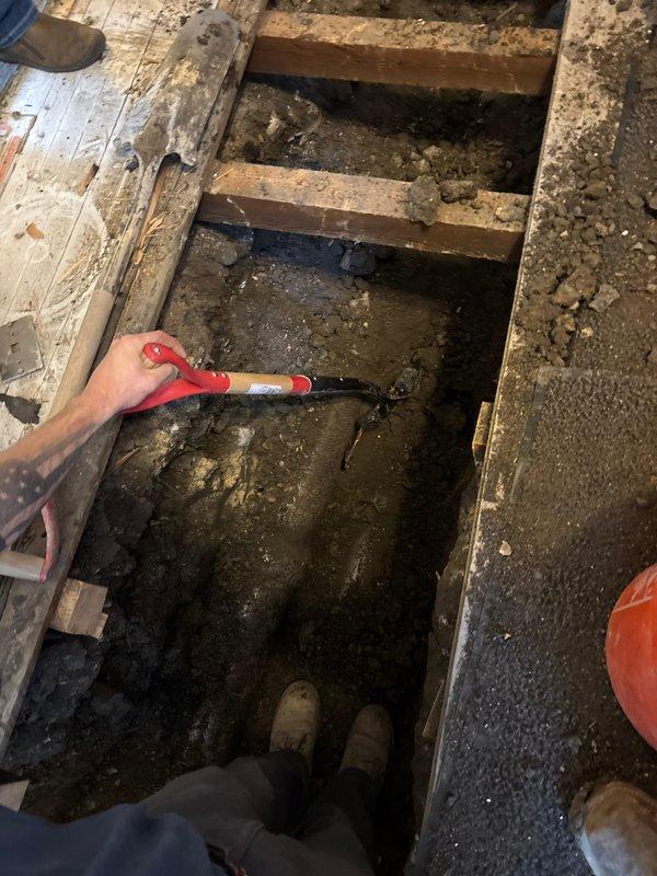 Excavated flooring and exposed subfloor joists to access and install new sewer line connection. Installed PVC pipe assembly with proper connections to existing drainage system. Client has paid initial deposit; remaining interior excavation work scheduled for December as per client's request.