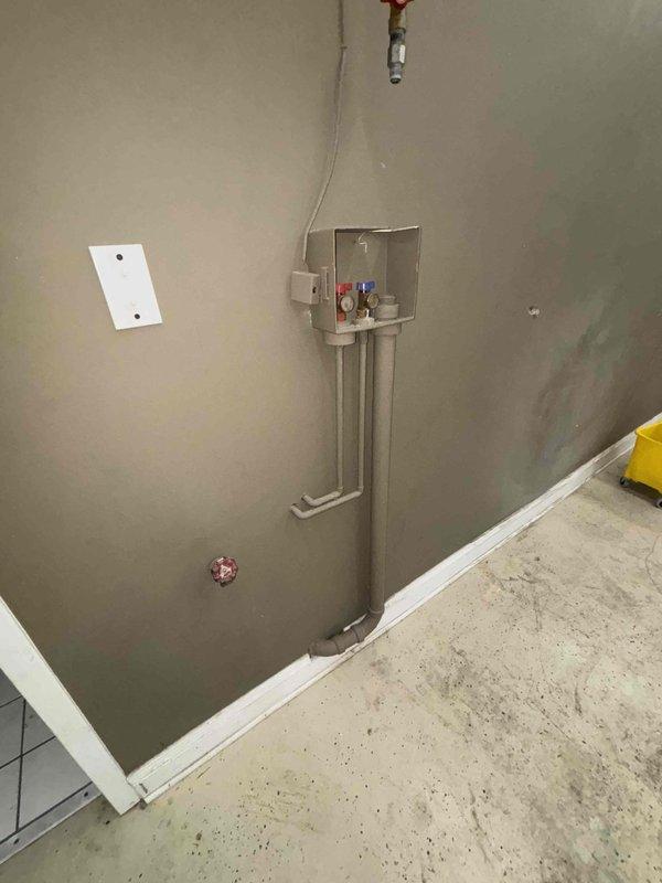 Conducted site assessment for soak sink installation in commercial garage/workshop space. Evaluated existing plumbing connections with hot and cold water valves and determined necessary fixture placement. Location features concrete flooring and adequate wall space for proper mounting and drainage requirements.