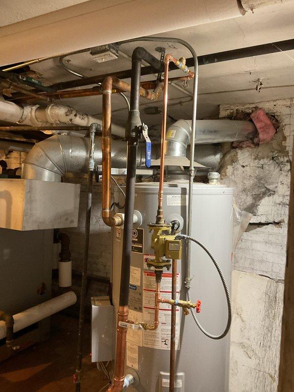 Completed installation of new water heater system in basement utility area, including copper piping connections, gas valve assembly, and all required fittings. System was properly mounted against existing masonry wall with appropriate clearances maintained. Final inspection confirmed no leaks and proper operation of all components.