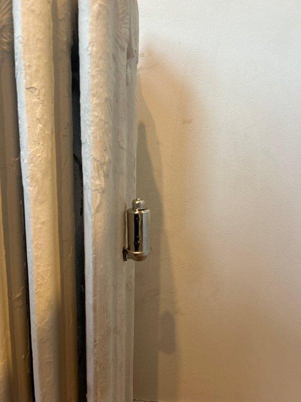 Serviced and inspected classic white cast iron radiator system. Identified and repaired door latch mechanism in adjacent doorway. All components now functioning properly with improved performance verified during final inspection.