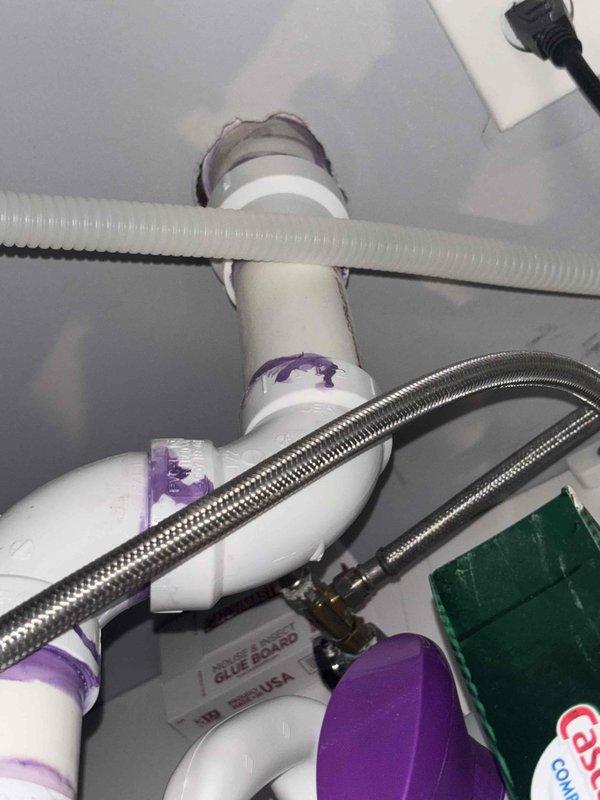 Performed comprehensive assessment of client's plumbing service requests including: evaluation of leaking toilet shut-off valve requiring replacement, assessment of kitchen area for new garbage disposal installation requiring initial setup, inspection of existing plumbing infrastructure to determine options for whole-home water filtration systems, and evaluation of toilet fixtures for potential bidet installation. Documented current plumbing conditions with photos showing existing water supply lines and PVC drainage system with visible primer markings at joints.