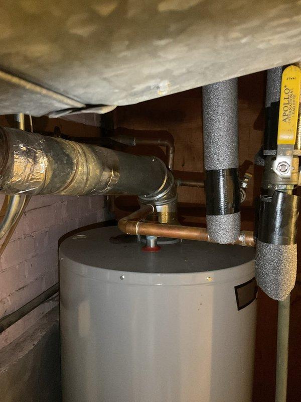 Inspected aging tank-style water heater (10-20 years old) and remedied two safety issues: installed missing temperature and pressure relief (T&P) valve discharge pipe and adjusted improper water heater vent piping to ensure proper exhaust flow.