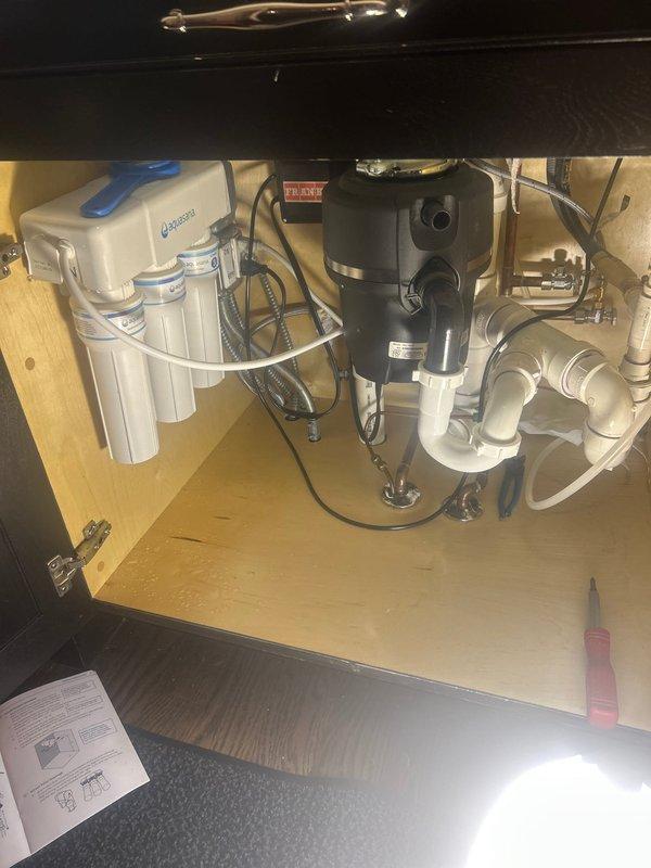 Successfully installed and connected a multi-stage water filtration system in the kitchen cabinet. System was properly mounted to cabinet wall and connected to existing plumbing, with operational testing confirming proper water flow through the new filtration unit.