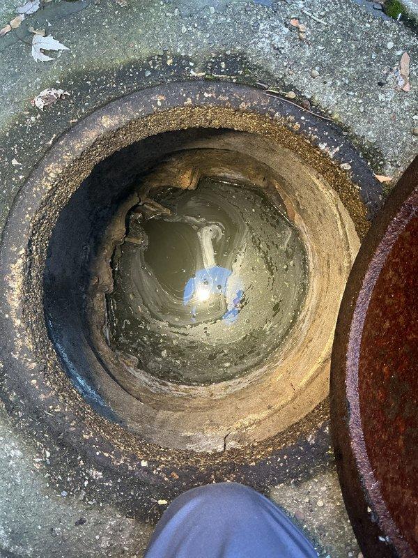 Performed service call transferred from Frank to Jon. Accessed manhole opening to inspect sewer line. Identified stagnant water and significant buildup in the drain pipe with visible deterioration and sediment accumulation. Documented condition with photos for assessment of necessary remediation.