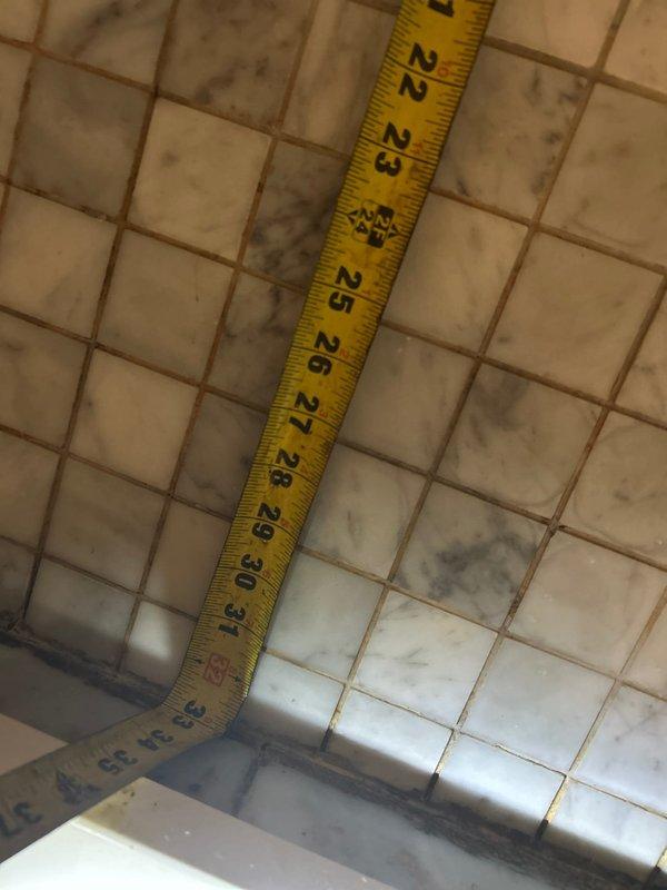 Conducted leak investigation for shower with intermittent ceiling leak below. Performed visual inspection of shower area, documenting measurements and examining tile conditions. Observed significant moisture damage at corner junctions, including mold/mildew accumulation and deteriorated grout lines, particularly where marble tile meets shower base, indicating potential waterproofing failure in shower pan area.