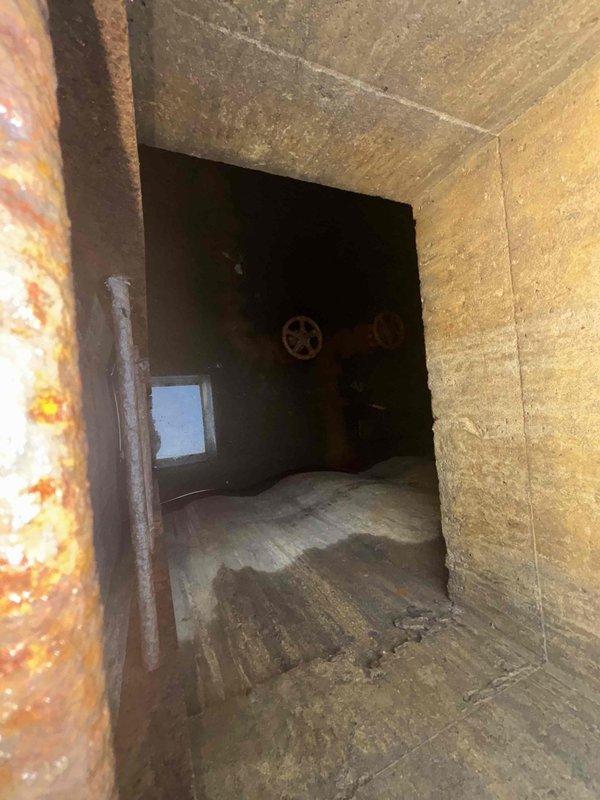 Conducted site inspection of four stuck water valves (4" or 5") in utility access area. Documented extensive pipe corrosion and deterioration within concrete enclosure. Photographed valve wheels showing significant rust and aging in difficult-to-access utility tunnel. Prepared quotation for valve replacement/repair as requested by client.