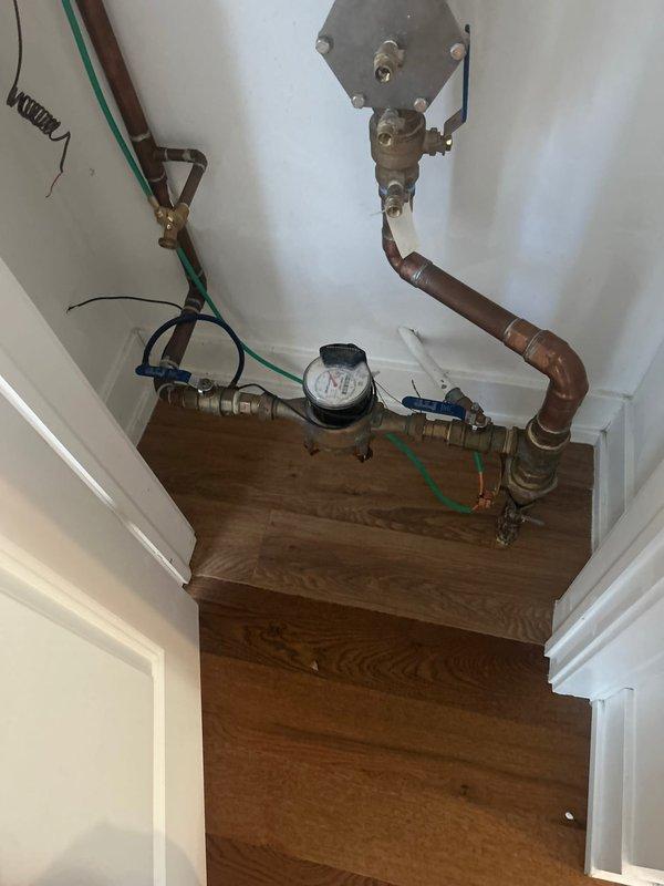 Inspected residential plumbing system for reported burst pipe. Examination revealed corrosion on copper pipes under kitchen sink with visible water damage to cabinet. Also inspected water meter assembly and associated valves in utility closet. Customer had already shut off water under kitchen sink to prevent leakage from external faucet when turned on.