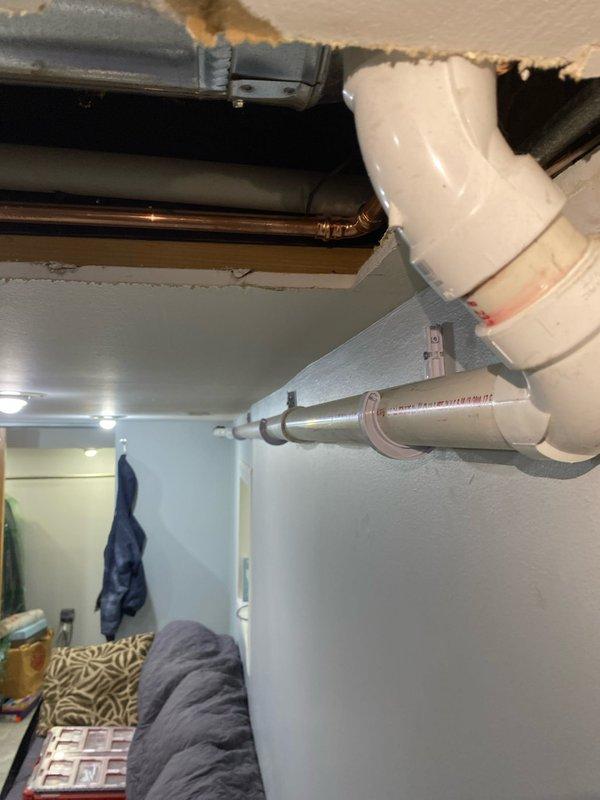 Completed installation of PVC drainage system with copper supply lines in residential area. Properly secured piping through ceiling access point and connected to existing plumbing infrastructure within the wall cavity. All connections were verified and tested for proper function.