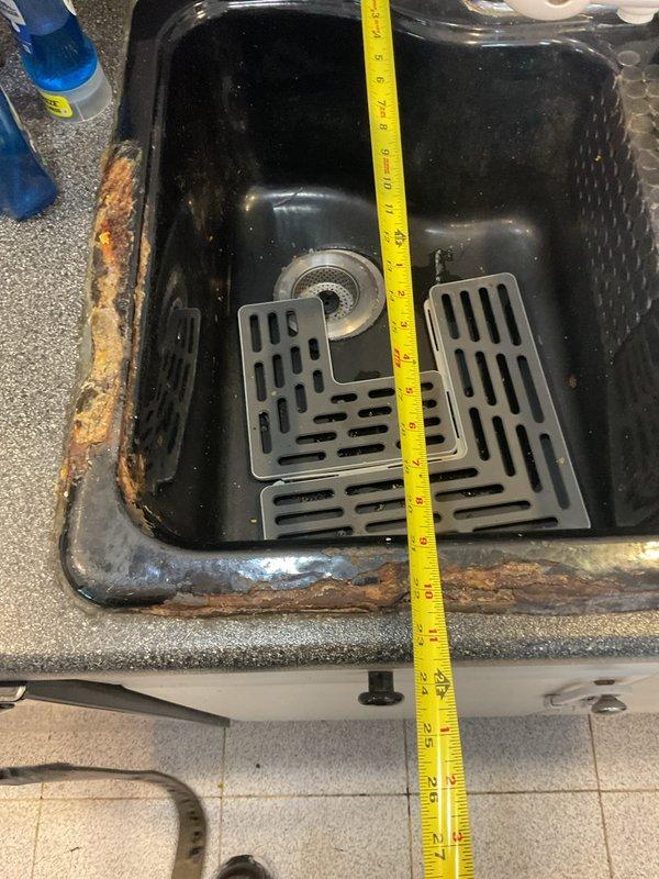 Responded to service call for slow draining tub with reported backup issues when washing machine and sink are used. Inspection revealed significant plumbing issues including a leaking P-trap under the kitchen sink with visible water damage to the cabinet floor and extensive rust corrosion along the sink edges. Recommended replacement of damaged P-trap assembly and sink due to deterioration, along with installation of new garbage disposal as requested.