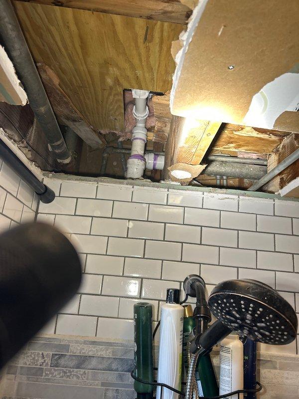 Responded to sold repair service (initially sold by Bryan C.) involving bathroom plumbing issues. Upon inspection, accessed ceiling area above bathroom to examine plumbing infrastructure, noting PVC connections with purple primer. Serviced bathtub/sink fixture and drain system, addressing water staining issues on the basin surface.