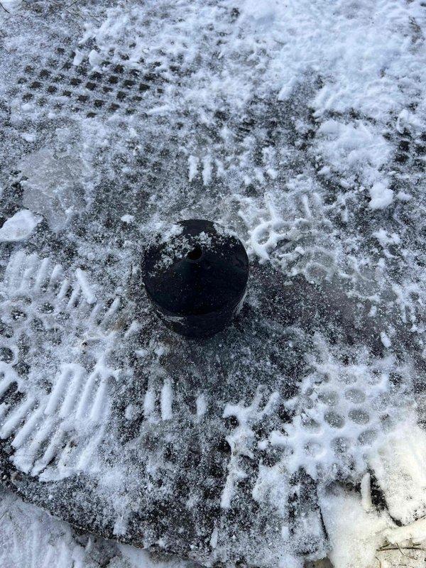 Responded to a service call for a drainage issue. Inspected a drainage pit containing stagnant water with significant mineral buildup, algae growth, and corrosion on metal components. Identified and accessed the exterior cleanout cap located in snow-covered ground to prepare for the scheduled repair work.