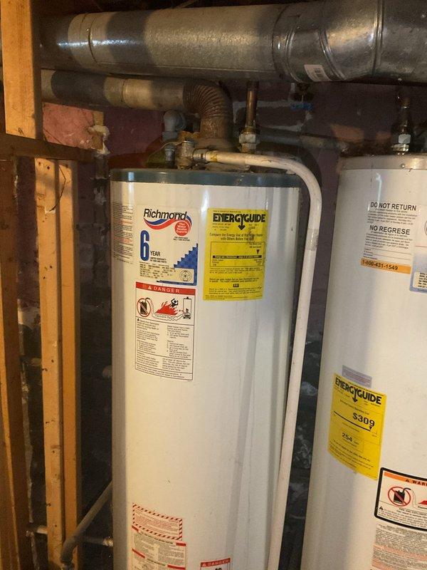 Performed diagnostic assessment on a leaking 50-gallon natural gas water heater approximately 20 years old. Inspection revealed significant corrosion at pipe connections and visible water damage to surrounding wooden structures. Observed rust formation on galvanized steel pipes, particularly at joint connections, indicating progressive deterioration. Recommended replacement of the aging unit due to its condition and exceeded service life expectancy.