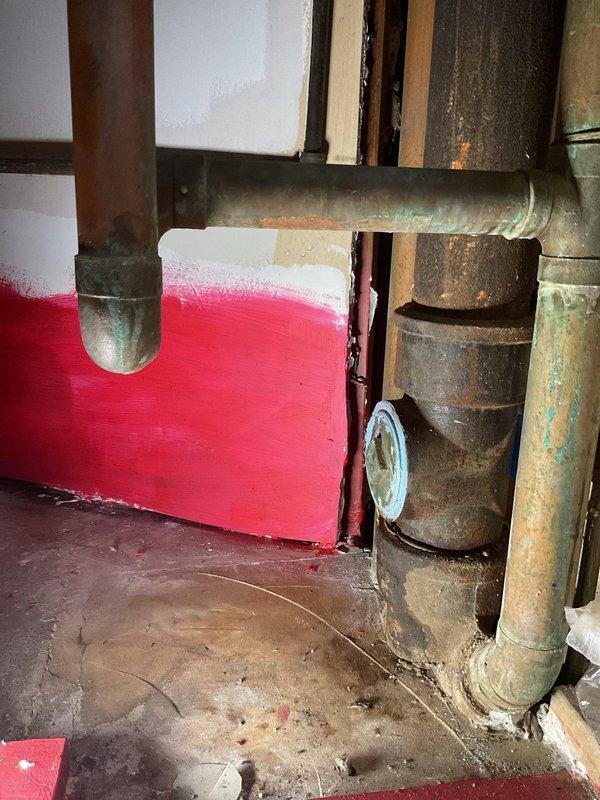 Responded to a clogged drain service call. Inspected aging copper plumbing system showing significant oxidation and a deteriorating cylindrical component with rust damage. Successfully cleared the blockage using specialized drain cleaning equipment in the basement utility area.