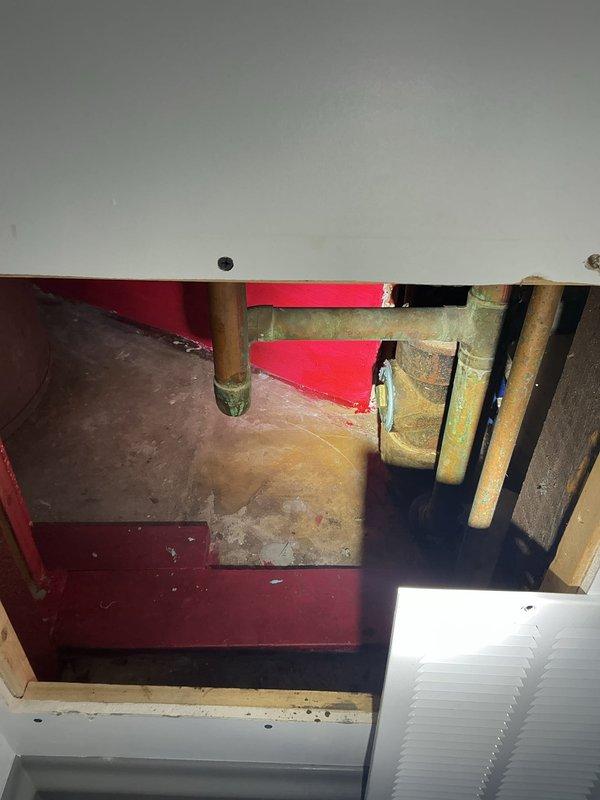 Conducted assessment for installation of cleanout and potential floor drain in unfinished basement with exposed brick walls and concrete flooring. Inspected existing plumbing infrastructure, noting copper pipes showing oxidation and greenish patina at joints. Observed cracked concrete floor and water damage, which will require consideration during installation planning.