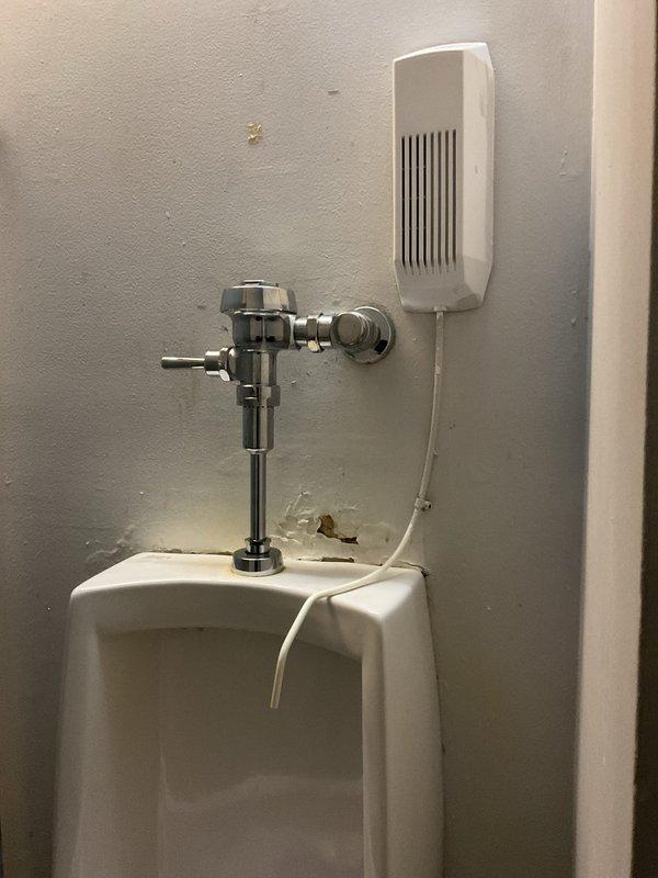 Successfully cleared clogged urinal in commercial restroom. Inspected chrome flush valve assembly and water supply connections, confirming proper operation after service. Noted minor wall damage near fixture base that may require future attention.
