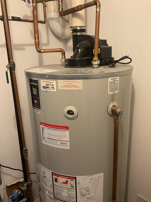 Performed assessment of existing residential water heater system for potential replacement. Current unit is aging with standard tank design featuring copper supply lines, circulator pump, and PVC venting system. Customer is interested in converting to a tankless water heater solution. Documented current installation configuration to prepare detailed conversion estimate.