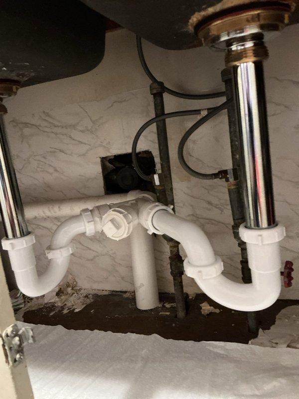 Responded to warranty service call for previously repaired kitchen sink drainage. Inspected the PVC P-trap assembly which had disconnected from the chrome tailpiece. Reassembled the connection between the chrome drain components and white PVC piping, ensuring proper alignment and secure fittings to prevent future leakage.