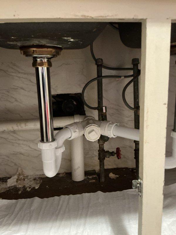 Responded to warranty service call for previously repaired kitchen sink drainage. Inspected the PVC P-trap assembly which had disconnected from the chrome tailpiece. Reassembled the connection between the chrome drain components and white PVC piping, ensuring proper alignment and secure fittings to prevent future leakage.