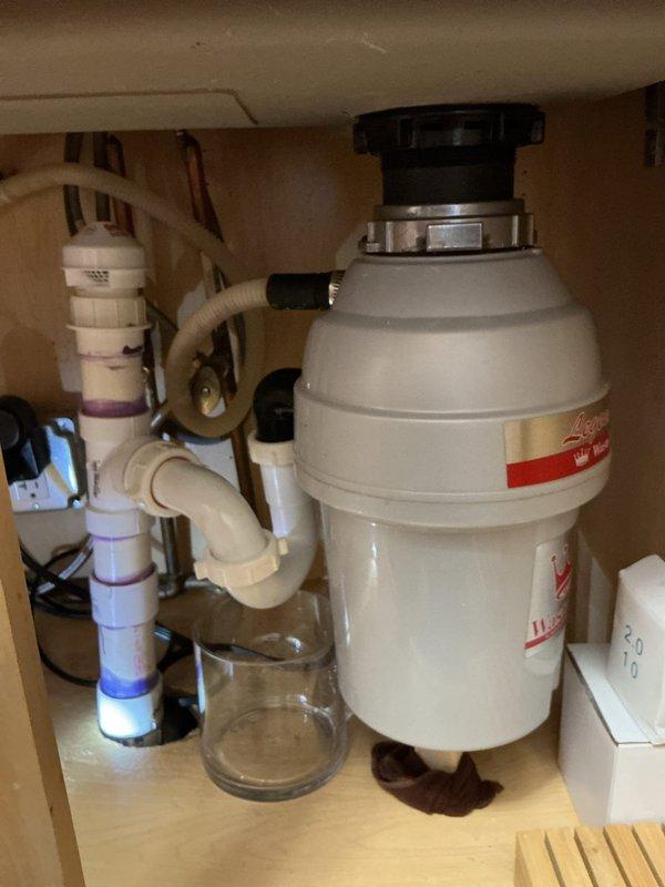 Completed replacement of malfunctioning garbage disposal unit in kitchen. Inspected existing under-sink plumbing configuration which included water filtration system with multiple components. Evaluated and reconfigured PVC drain connections to accommodate new disposal installation. System tested for proper drainage and operation following replacement.