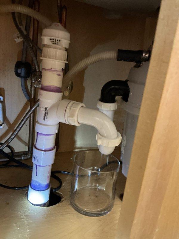 Completed replacement of malfunctioning garbage disposal unit in kitchen. Inspected existing under-sink plumbing configuration which included water filtration system with multiple components. Evaluated and reconfigured PVC drain connections to accommodate new disposal installation. System tested for proper drainage and operation following replacement.