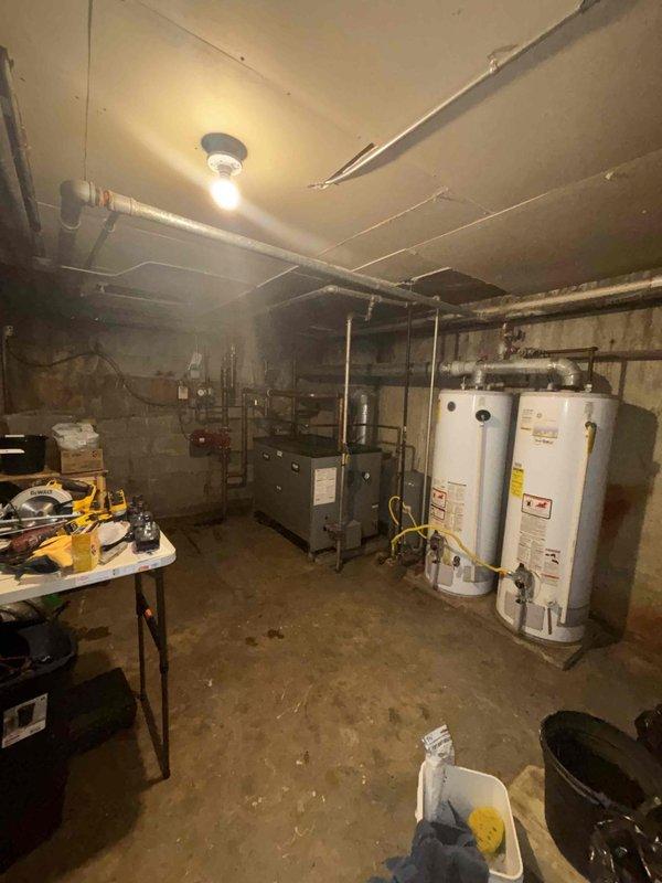 Conducted assessment of two aging 50-gallon water heaters in basement utility room requiring replacement. Noted significant copper pipe corrosion with extensive oxidation and mineral buildup on main supply line. Documented moisture-related issues including wall staining and concrete floor discoloration that may affect installation parameters. Prepared comprehensive replacement estimate as requested by customer through home comfort referral.