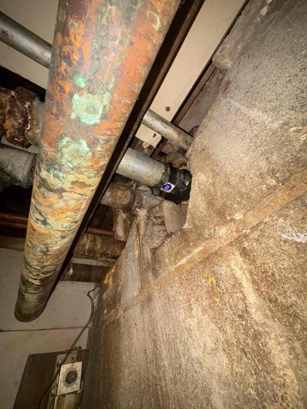 Conducted assessment of two aging 50-gallon water heaters in basement utility room requiring replacement. Noted significant copper pipe corrosion with extensive oxidation and mineral buildup on main supply line. Documented moisture-related issues including wall staining and concrete floor discoloration that may affect installation parameters. Prepared comprehensive replacement estimate as requested by customer through home comfort referral.