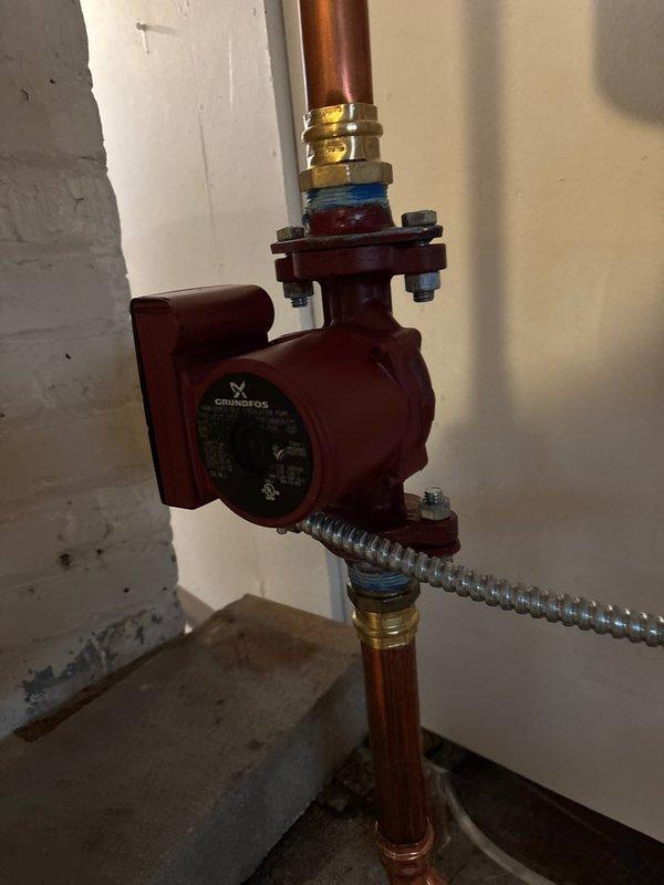 Replaced existing circulator pump with properly sized Grundfos UP15-42F non-submersible pump to address humming noise in baseboard heating system. Verified proper installation with correct flow direction as indicated by color-coded fittings. System is now operating efficiently with reduced noise, though customer was advised about pre-existing odor from one radiator that requires separate investigation.