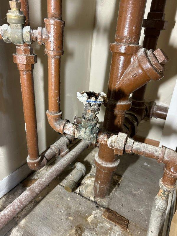 Inspected residential drain and sewer system, identifying heavily corroded water valve with significant scale buildup requiring replacement. Observed multiple copper pipes with mineral deposits and corrosion at connection points, particularly at the central valve where bluish-white deposits were evident. Customer advised to contact city authorities regarding removal of B-box top before proceeding with necessary repairs.