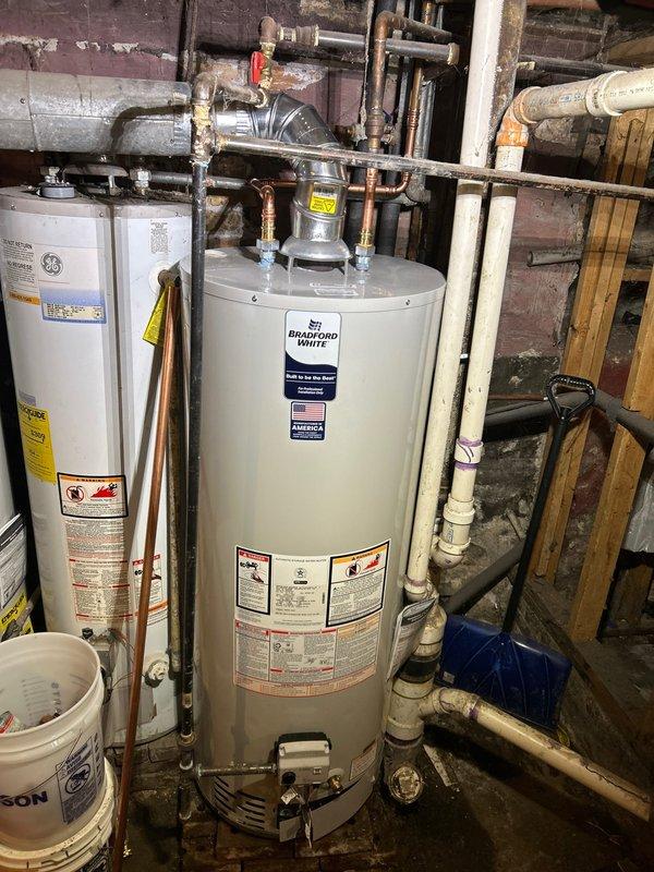 Successfully installed a Bradford White tanked water heater in utility area with proper venting and copper pipe connections. Installation included necessary valves and fittings while adhering to the 56" height restriction requirement by using a standard/low profile model rather than slim design. All components were properly secured with no leaks observed during final inspection.