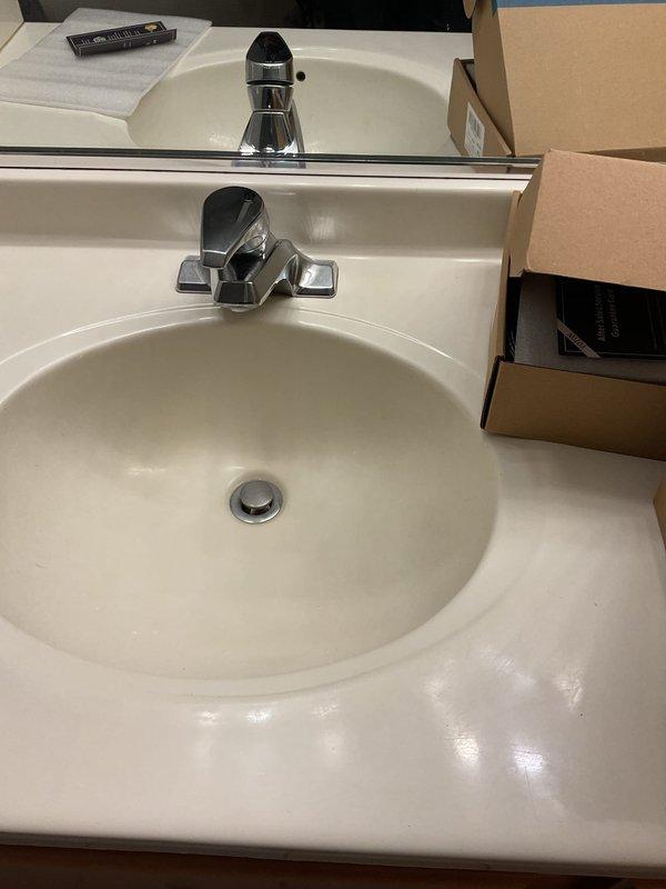 Successfully installed customer-supplied toilet in bathroom with closed lid, circular flush button, and water efficiency features. Verified proper seating on beige tile floor, confirmed water supply connection, and tested flush operation to ensure no leaks. Also installed two customer-supplied faucets as requested, with final inspection confirming all plumbing fixtures functioning properly.