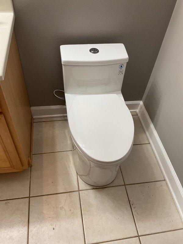 Successfully installed customer-supplied toilet in bathroom with closed lid, circular flush button, and water efficiency features. Verified proper seating on beige tile floor, confirmed water supply connection, and tested flush operation to ensure no leaks. Also installed two customer-supplied faucets as requested, with final inspection confirming all plumbing fixtures functioning properly.