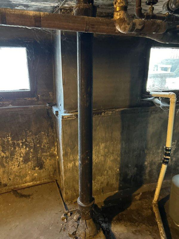 Conducted evaluation of century-old home for bathtub replacement. Current bathroom features white subway tile walls with standard tub, safety grab bar, and hexagonal tile flooring. Basement inspection revealed significant water damage and deterioration with visible staining on concrete walls, suggesting long-term moisture issues that must be addressed before fixture replacement proceeds.
