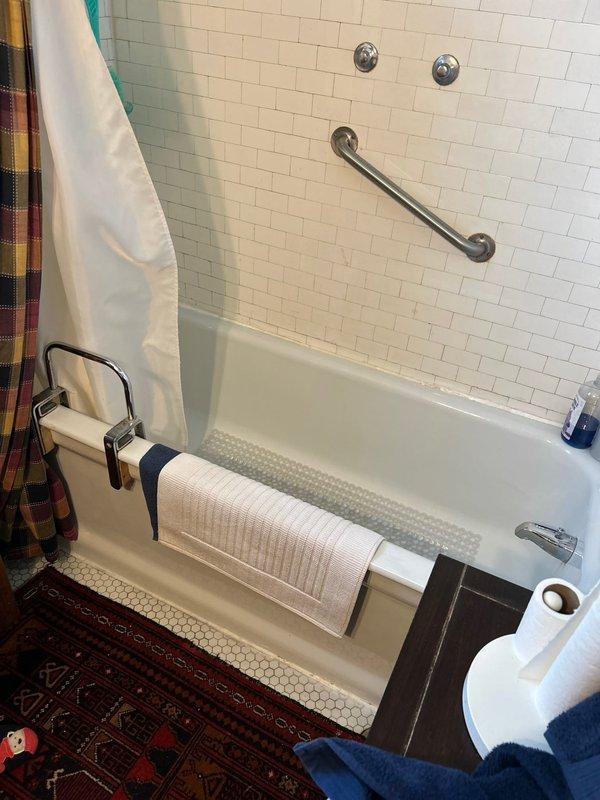 Conducted evaluation of century-old home for bathtub replacement. Current bathroom features white subway tile walls with standard tub, safety grab bar, and hexagonal tile flooring. Basement inspection revealed significant water damage and deterioration with visible staining on concrete walls, suggesting long-term moisture issues that must be addressed before fixture replacement proceeds.