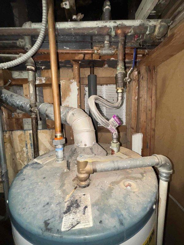 Inspected two residential water heater units in utility area - one Richmond model and one older unit with blue-gray top. Both units showed normal wear with functional plumbing connections including copper, PVC, and galvanized steel piping. Evaluated systems for replacement options based on current installation configuration and client's requirements for improved capacity.