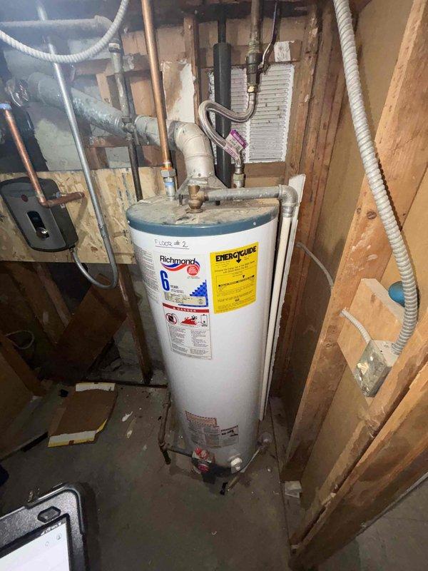 Inspected two residential water heater units in utility area - one Richmond model and one older unit with blue-gray top. Both units showed normal wear with functional plumbing connections including copper, PVC, and galvanized steel piping. Evaluated systems for replacement options based on current installation configuration and client's requirements for improved capacity.