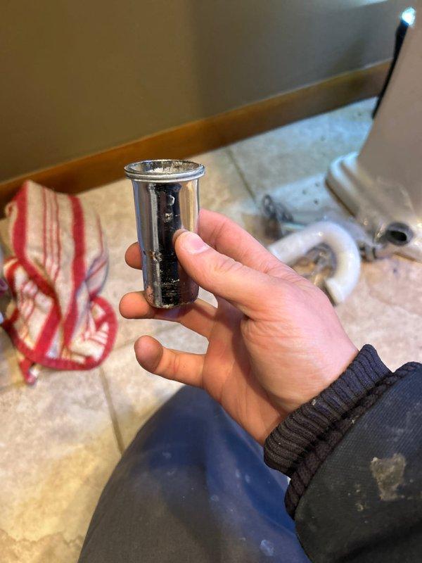 Performed service on bathroom pedestal sink due to reported leak. Removed drain assembly components which showed signs of mineral buildup and wear. Successfully diagnosed and repaired the issue by replacing the corroded drain trap extension, then verified proper drainage and absence of leaks after installation.