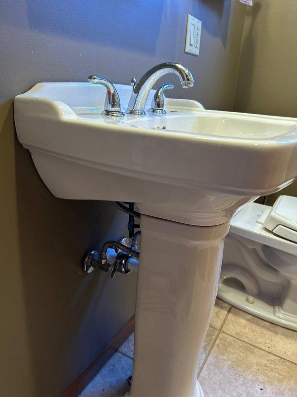 Performed service on bathroom pedestal sink due to reported leak. Removed drain assembly components which showed signs of mineral buildup and wear. Successfully diagnosed and repaired the issue by replacing the corroded drain trap extension, then verified proper drainage and absence of leaks after installation.