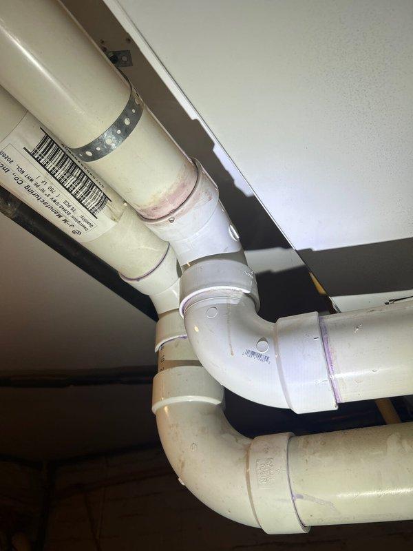 Returned to complete toilet/urinal service requiring two technicians. Installed new PVC drainage pipes with proper elbow joints and secure mounting brackets in utility area. Addressed plumbing infrastructure in basement mechanical room where ventilation system connects to water heater unit. All connections properly secured and tested for functionality.