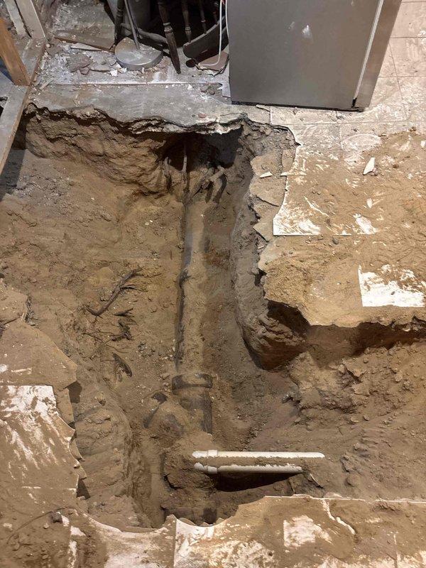 Completed excavation of interior floor to access and install new main sewer line. Exposed existing vertical drainage pipe and installed horizontal PVC pipe connection in the excavated area. Work was performed as part of a financed project sold by Jon.