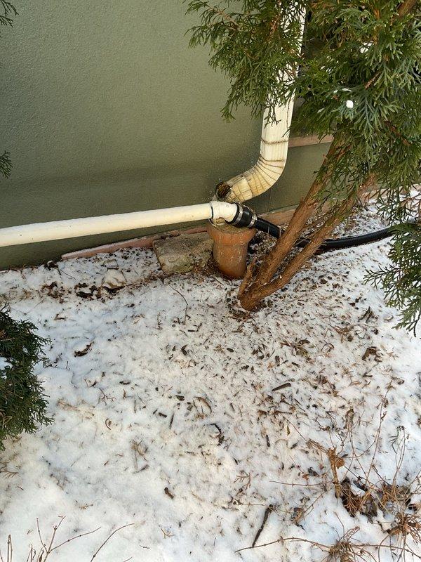 Responded to emergency call regarding sump pump backup causing flooding. Inspected wooden floor access point to sump pump system and examined exterior drainage configuration including downspout connection to drain pipe. Identified aged system with potential blockage issues. Completed necessary repairs to restore proper drainage function and prevent further water intrusion.