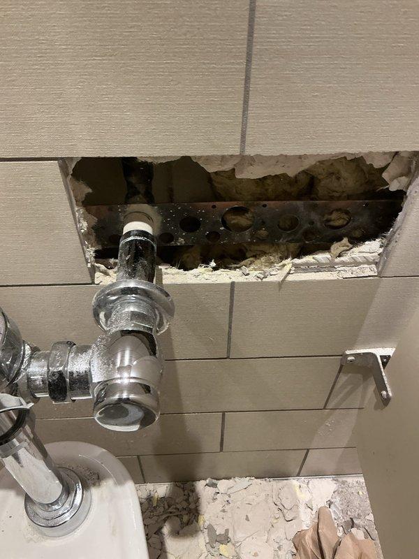 Completed repair work on bathroom plumbing fixture by accessing the wall through tile removal. Exposed and addressed issues with the in-wall plumbing pipes, which showed 90-degree bends requiring service. Repaired the affected plumbing components behind the wall cavity as sold by Brian.