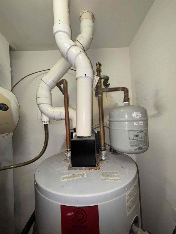 Inspected 19-year-old water heater system exhibiting excessive noise and visible mineral deposits around pipe connections. Visual assessment confirmed significant sediment buildup and corrosion at connection points, consistent with end-of-life system performance. Recommended replacement due to age exceeding typical service life and deteriorating condition.