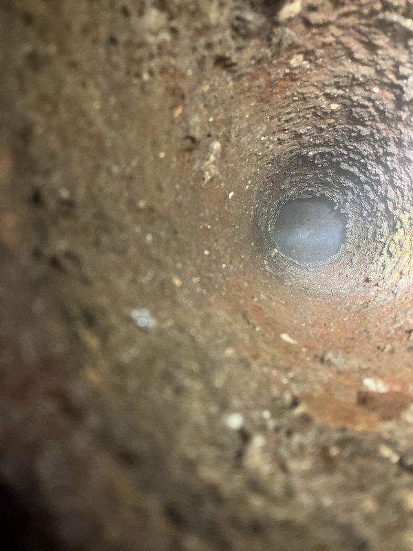 Performed comprehensive sewer evaluation per client's request following previous inspection. Documented significant corrosion and oxidation on copper piping system, particularly on green copper pipe with curved elbow joint. Inspection revealed interior pipe deterioration with substantial rust/sediment buildup and rough texture indicating advanced aging of the system, confirming inspector's recommendation for p-trap installation.
