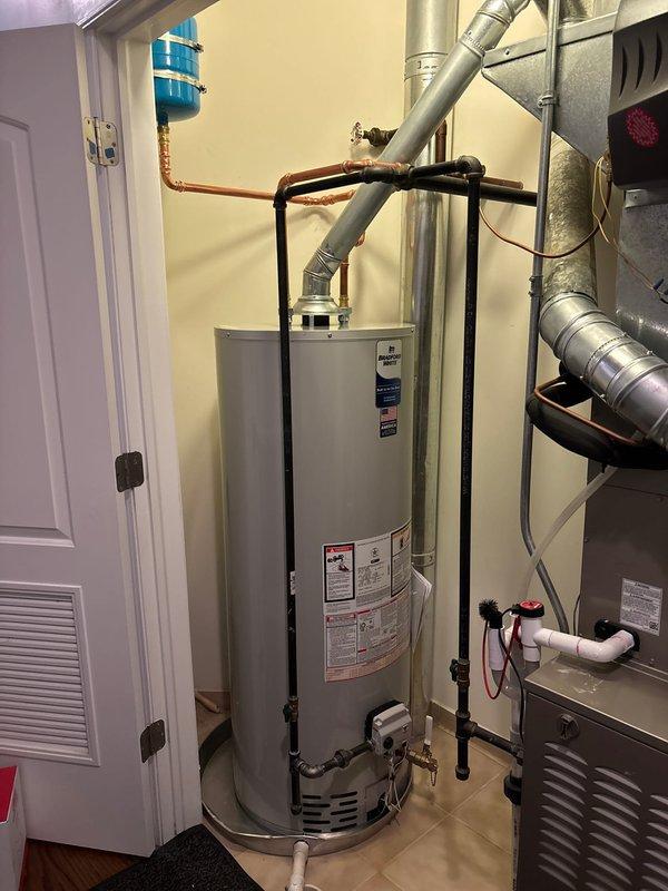 Completed installation of new tanked water heater with proper piping connections. Mounted expansion tank securely to wall with metal straps and installed all necessary copper supply lines. System was tested and is functioning correctly with no leaks detected.