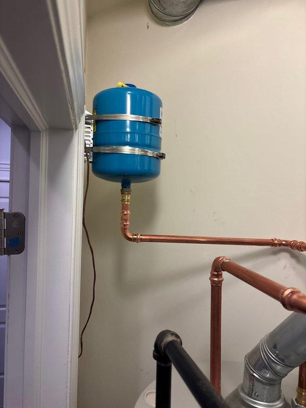 Completed installation of new tanked water heater with proper piping connections. Mounted expansion tank securely to wall with metal straps and installed all necessary copper supply lines. System was tested and is functioning correctly with no leaks detected.