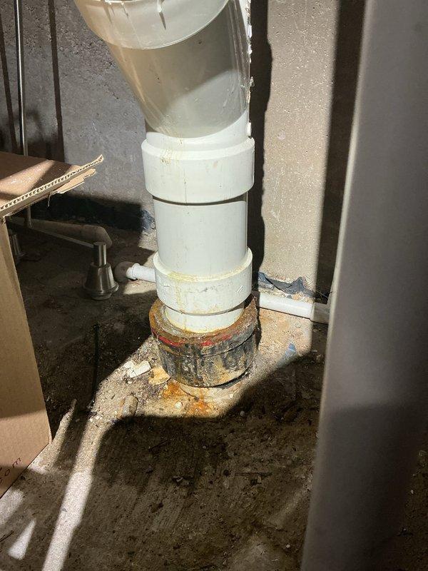 Responded to call-back for Jon regarding rusted and deteriorated pipe connection. Inspected basement plumbing system and identified significant corrosion at PVC pipe base where it connects to floor drain, with visible rust stains spreading onto concrete. Documented condition with photos for service record.