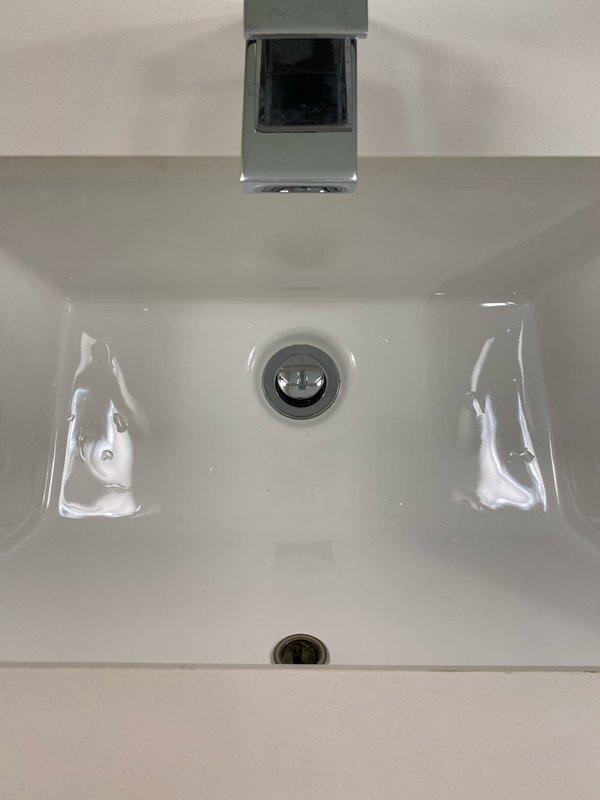Completed installation of new bathroom fixtures as sold by Tyler. Installed contemporary chrome faucet with square design on rectangular white porcelain sink and mounted modern toilet with square-shaped tank against beige wall. All fixtures were properly secured and tested for functionality.