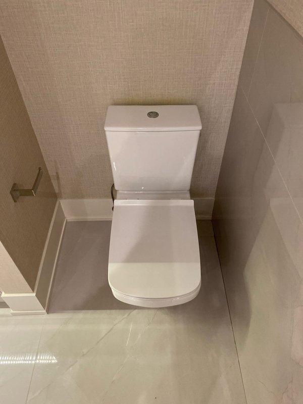 Completed installation of new bathroom fixtures as sold by Tyler. Installed contemporary chrome faucet with square design on rectangular white porcelain sink and mounted modern toilet with square-shaped tank against beige wall. All fixtures were properly secured and tested for functionality.